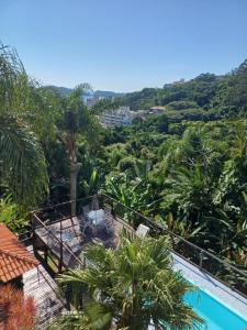 a view of a resort with a pool and palm trees at Suíte Atlântica com banheira de hidromassagem in Bombinhas