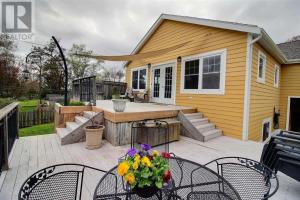 a patio with a table and chairs and a house at Private Two Queen Beds Room Near UPEI & Downtown Cozy Retreat Near Everything in Charlottetown
