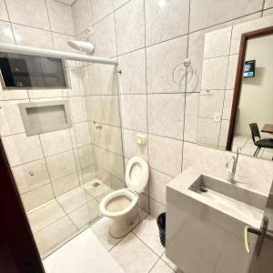 a bathroom with a toilet and a shower and a sink at Hotel Rio Grande in Dourados