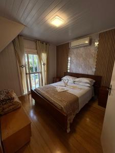 a bedroom with a large bed and a window at casarosaencantada -villaencantorosa in Gramado
