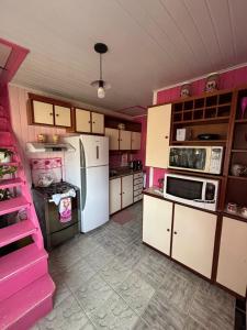 a kitchen with pink cabinets and a white refrigerator at casarosaencantada -villaencantorosa in Gramado