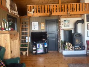 a living room with a tv and a wooden ceiling at Hannebu, hytte med 3 soverom, 2 bad og sovehems in Kyrkjebygdi
