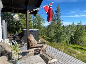 a wooden deck with a bench and a flag at Hannebu, hytte med 3 soverom, 2 bad og sovehems in Kyrkjebygdi