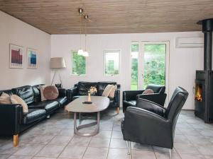 a living room with black leather furniture and a table at 8 person holiday home in Ørsted in Kare