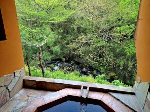 a room with a window with a view of a forest at ローズウッドガーデンアンドヴィラ-Private Onsen Villa in Nasu- in Nasu