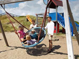 una famiglia seduta su un'altalena in un parco giochi di 6 person holiday home in Ringkøbing a Ringkøbing