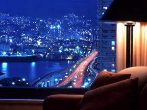 Kobe Bay Sheraton Hotel & Towers في كوبه: اطلالة على المدينة ليلا من النافذة