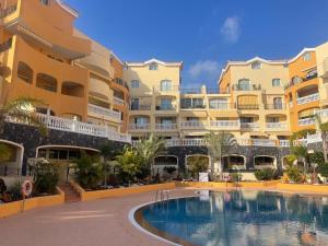 a hotel with a swimming pool in front of a building at Apartamento Pargue Tropical in Los Cristianos