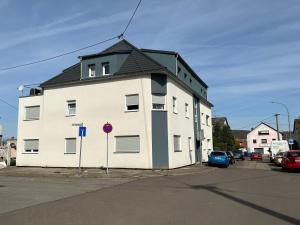 a white building with a black roof on a street at Appartement Heidstock in Völklingen