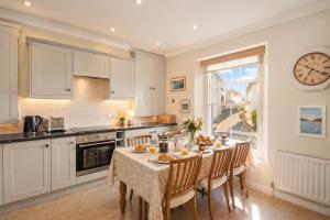 a kitchen with a table and chairs and a clock on the wall at The Old Post Office - Parking Available - 75 meters Estuary in Salcombe