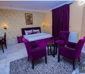 a bedroom with a bed and a couch and chairs at Benyster Hotel in Gwarinpa
