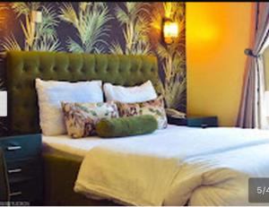 a bedroom with a bed with a green headboard and pillows at Benyster Hotel in Gwarinpa