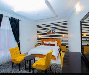 a bedroom with a bed and two yellow chairs at Benyster Hotel in Gwarinpa +4 photos