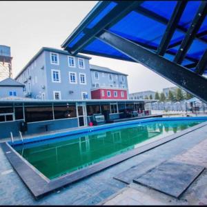 an empty swimming pool with buildings in the background at Benyster Hotel in Gwarinpa