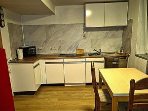 a kitchen with white cabinets and a table and a sink at Ferien & Monteure Residence in Schauenburg