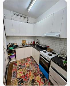 a kitchen with white cabinets and a rug on the floor at Euro Nomads in Melbourne