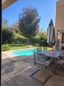 a table with an umbrella next to a swimming pool at Casa chacras in Chacras de Coria