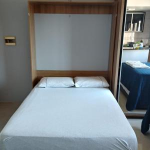 a bedroom with a large white bed in a room at Flat ao lado do Shopping in Santa Cruz do Sul +3 photos