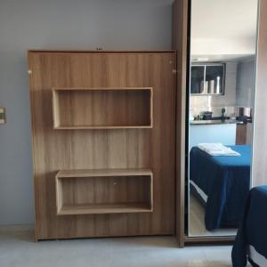 a wooden door with a mirror next to a bedroom at Flat ao lado do Shopping in Santa Cruz do Sul
