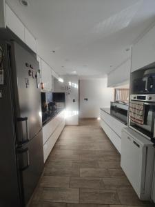 a large kitchen with white cabinets and a tile floor at Casa chacras in Chacras de Coria