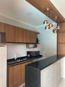 a kitchen with a black counter top and wooden cabinets at Maria Luiza da silva in Japaratinga