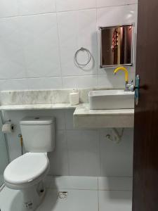 a white bathroom with a toilet and a sink at Maria Luiza da silva in Japaratinga