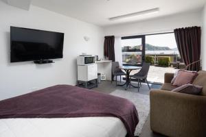 a hotel room with a bedroom with a bed and a television at Harbour View Motel in Picton