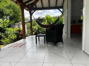 a porch with a hammock and a table and chair at Maison cosy à Lamentin, 20m², climatisation in Lamentin