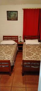 a room with two beds and a red curtain at Agradable casa al lado de la playa in Las Cruces
