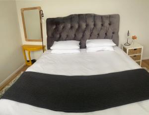 a bedroom with a large bed with a black headboard at Railway Cottage at Rawdons Country Estate in Nottingham Road