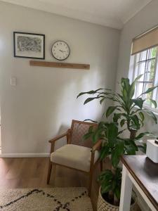 a living room with a chair and a clock on the wall at Railway Cottage at Rawdons Country Estate in Nottingham Road