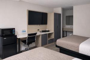 a hotel room with two beds and a desk with a television at Fair Motel in Upper Saddle River +3 photos