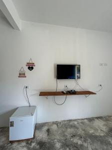 a room with a tv on a white wall at Pousada Villa Japa in Maragogi