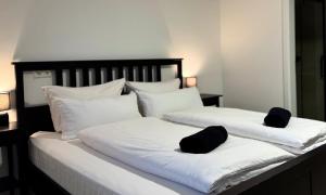 two white beds with black pillows on top of them at PW38 Studio Koblenz in Koblenz