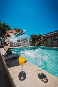 two glasses of orange juice sitting on a table next to a swimming pool at Villa JOSANA in Sarandë