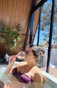 a woman in a bathtub drinking a glass of wine at Refúgio romântico em Pirenópolis Chalé Ypê Branco Ypês da Serra in Pirenópolis
