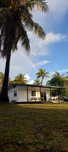 a house with a palm tree in front of it at Heaiti Lodge in Avatoru