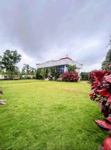 a building with a green field in front of it at Mir's Farm House in Hyderabad