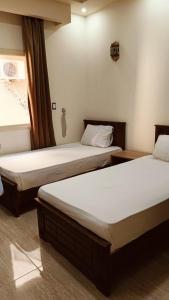 two twin beds in a room with a window at The Palace Dahab in Dahab