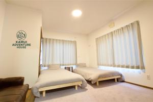a room with two beds and a couch and a window at Kamui Adventure House in Asahikawa