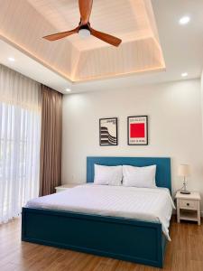 a bedroom with a blue bed with a ceiling fan at Solara Coast Villa in Tiến Thành