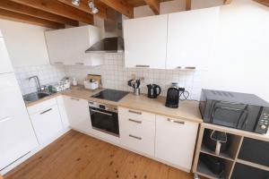 a kitchen with white cabinets and a microwave at Loft Chaleureux - Le Chalet Montois in Mons