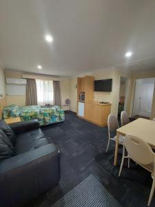 a room with a couch and a bed and a table at All Seasons Motor Lodge in Dubbo