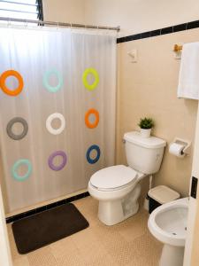 a bathroom with a toilet and a shower curtain at Villa Odalys Cozy Mexican style house in Mérida +8 photos