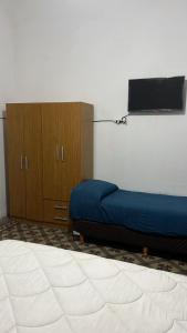 a bedroom with a blue bed and a tv on the wall at La Esperanza in Deán Funes