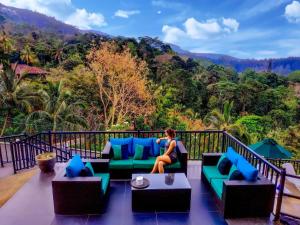 a woman sitting on a couch on a balcony at Grand Hills kandy in Kandy