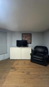 a living room with a black leather chair and a screen at La Esperanza in Deán Funes