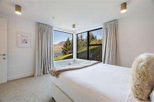 a bedroom with a bed and a large window at Vanda Heights in Queenstown