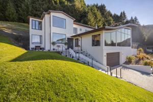 a house on a hill with a green lawn at Vanda Heights in Queenstown