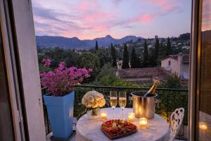 a table with wine glasses and a bowl of fruit on a balcony at Villa Del Sol with Mountain Views in Vence